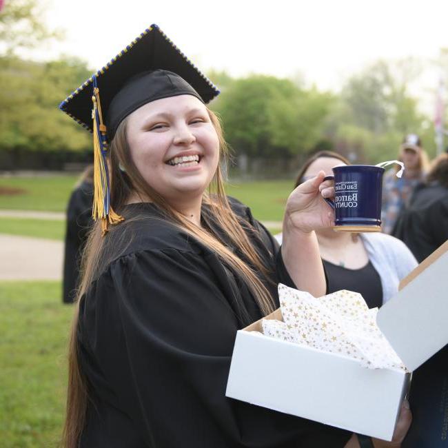 female graduate holding a UW-Eau Claire Barron County coffee mug